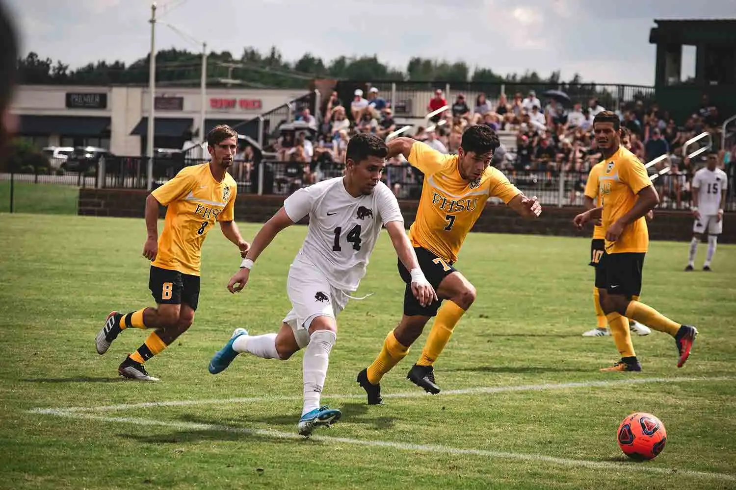 College soccer players competing for the ball in front of a crowd